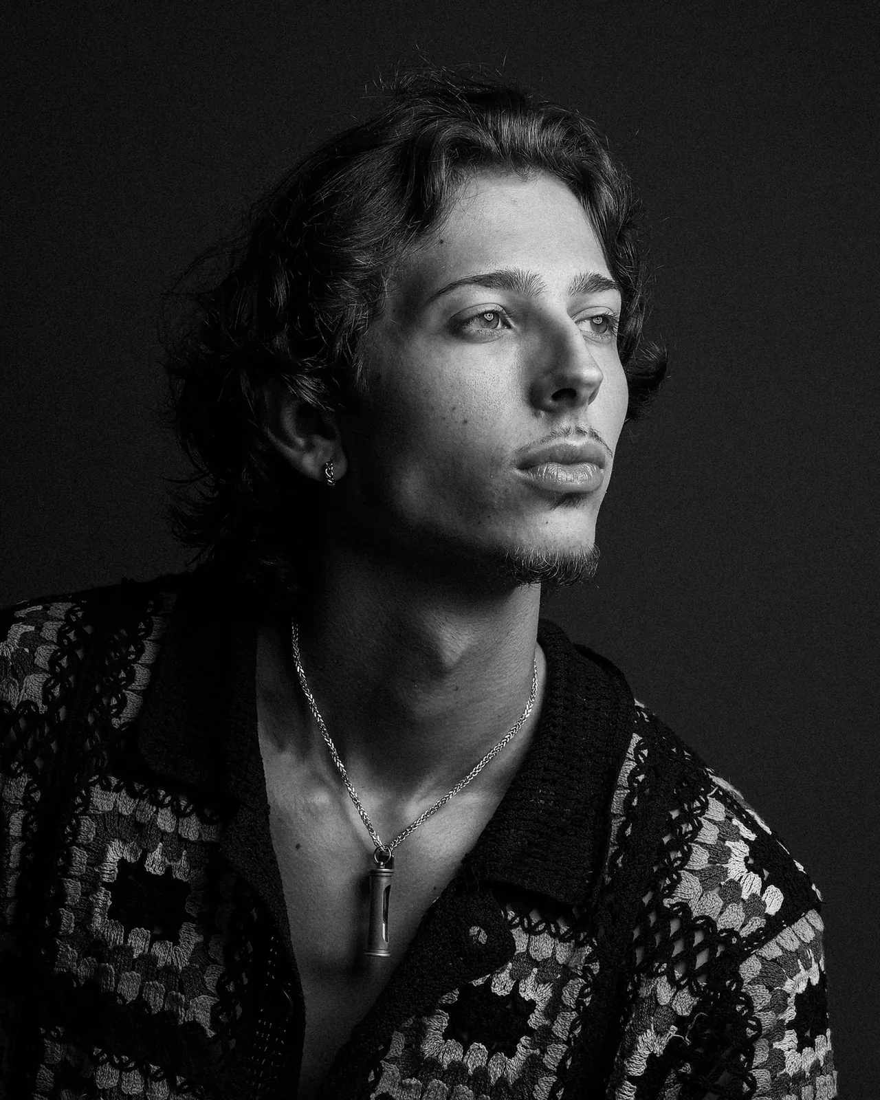 Black and white studio portrait of a young man in a crochet shirt, directed lighting, New Haven County