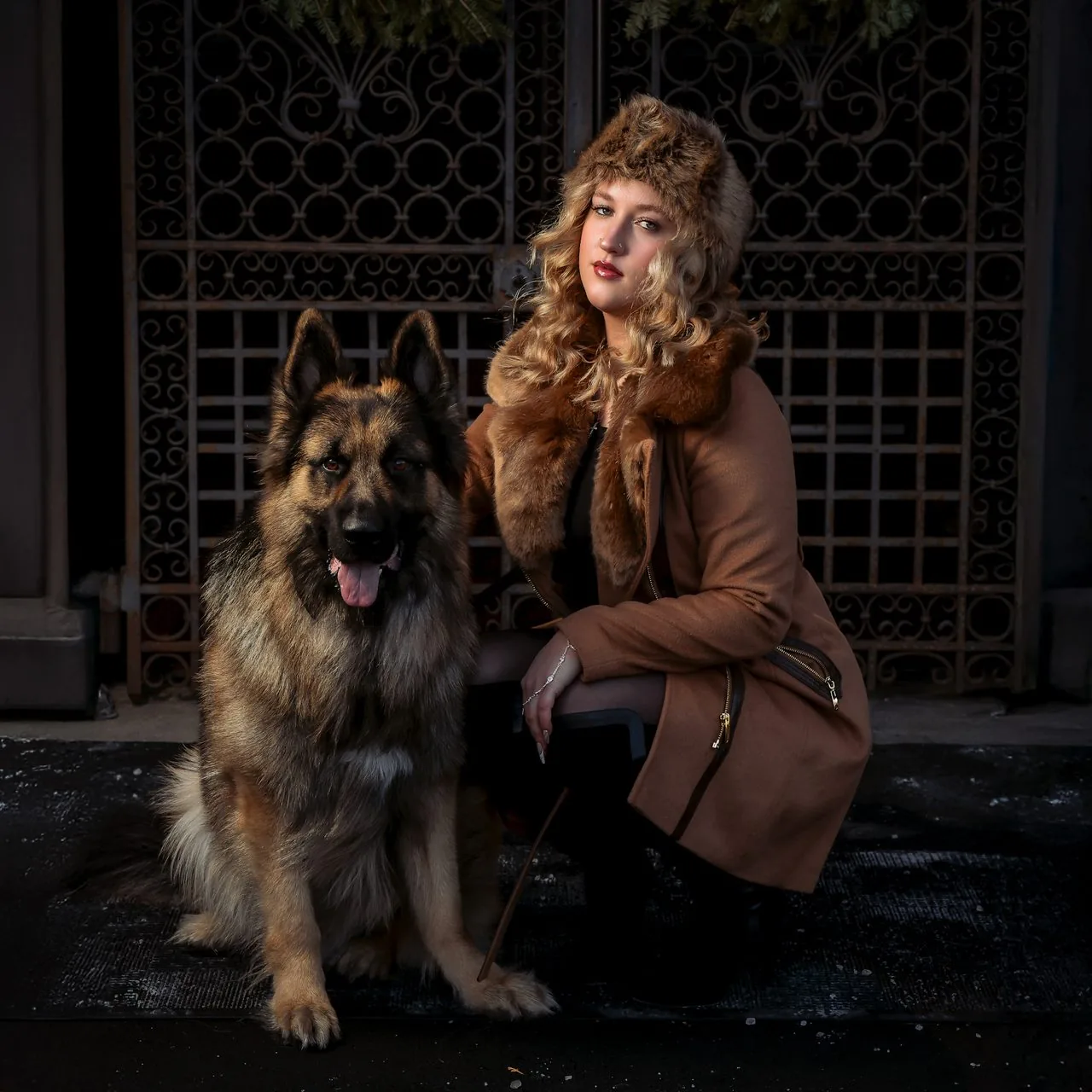 Winter evening portrait of a woman with her German Shepherd by wrought-iron gates in Connecticut