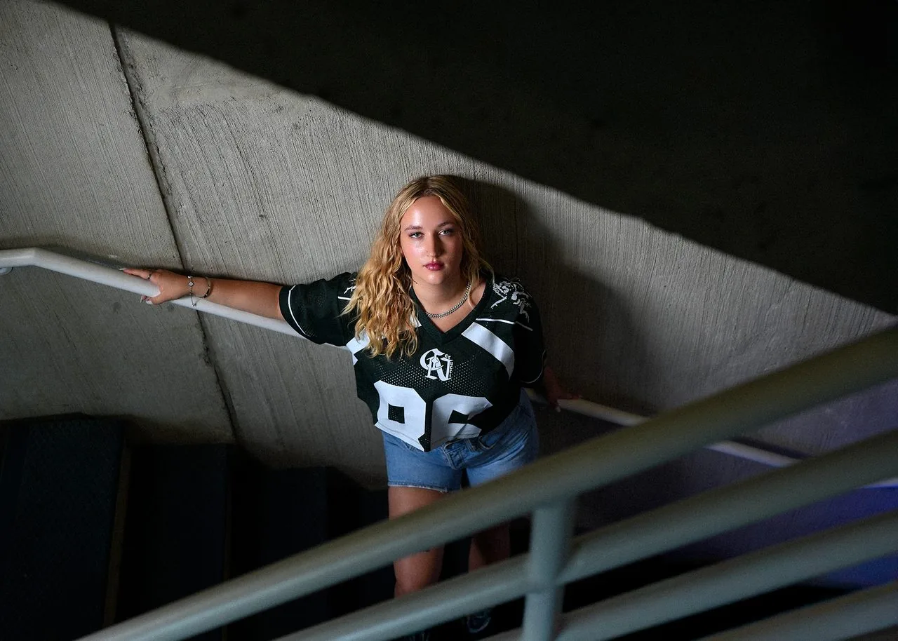Urban senior picture of a blonde student in a sports jersey in a concrete stairwell, Connecticut