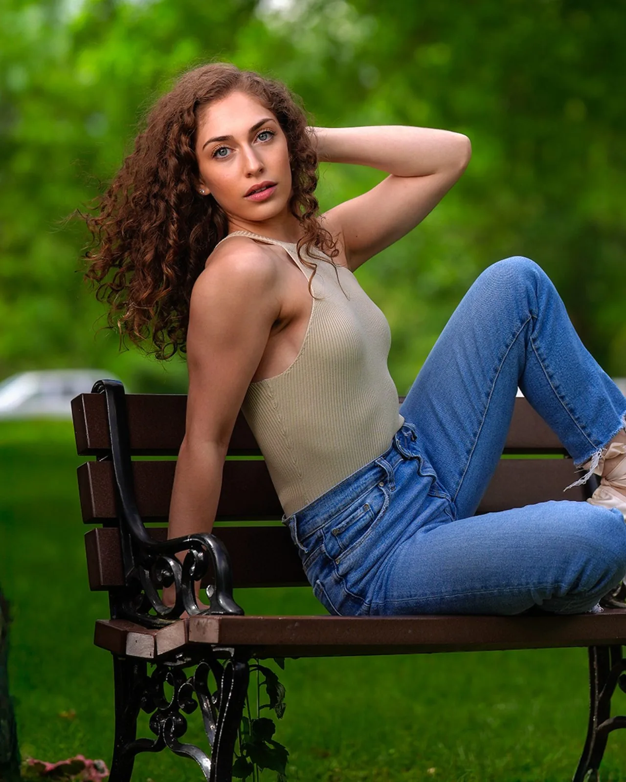 Relaxed high school senior portrait of a curly-haired dancer on a park bench, summer greenery, CT