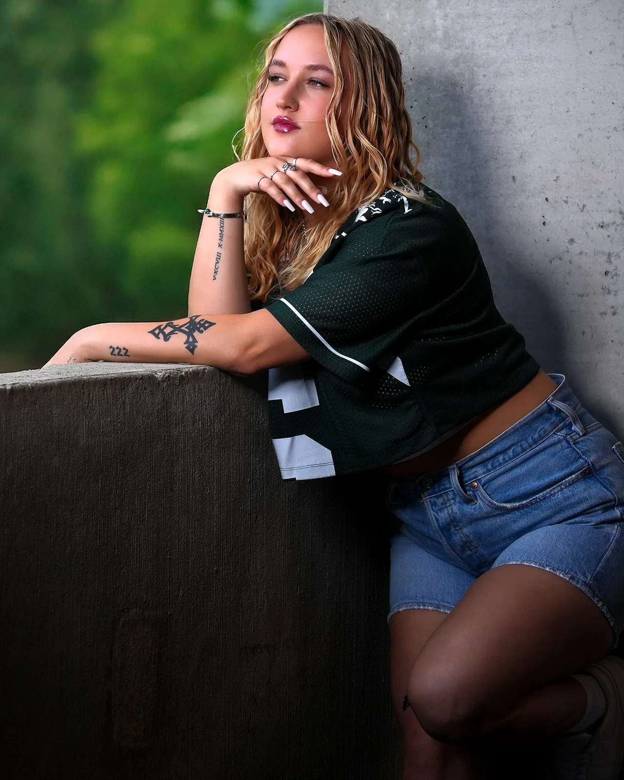 Edgy senior portrait of a student in a football jersey leaning on a concrete ledge, Connecticut